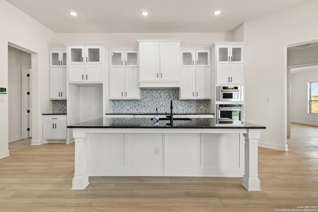 a large kitchen with stainless steel appliances granite countertop a stove a sink and white cabinets