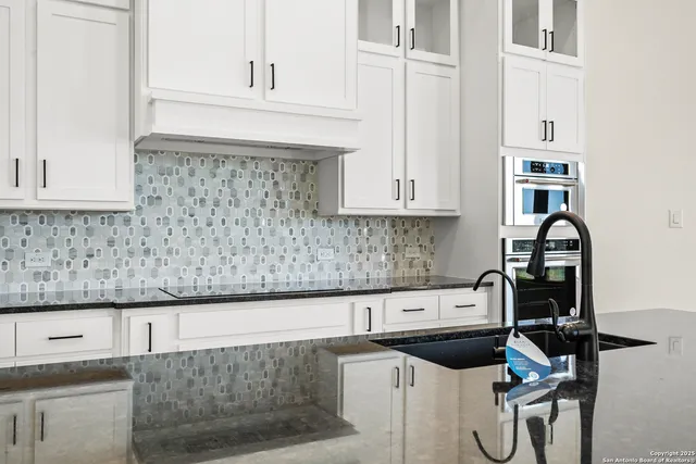 a kitchen with granite countertop a sink stove and cabinets