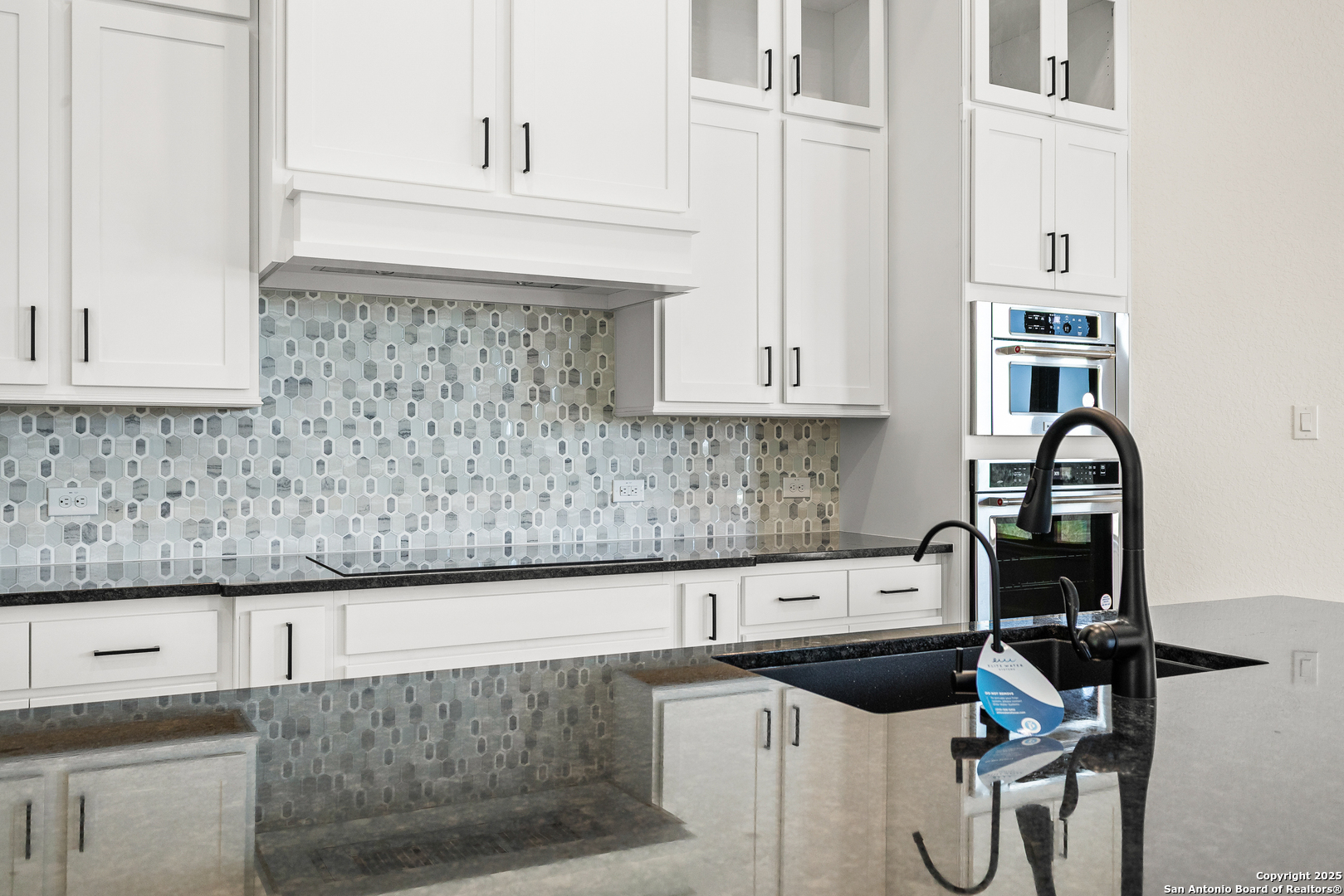 241 Stone Loop Castroville, TX 78009 - Photo 14 of 37 a kitchen with granite countertop a sink stove and cabinets