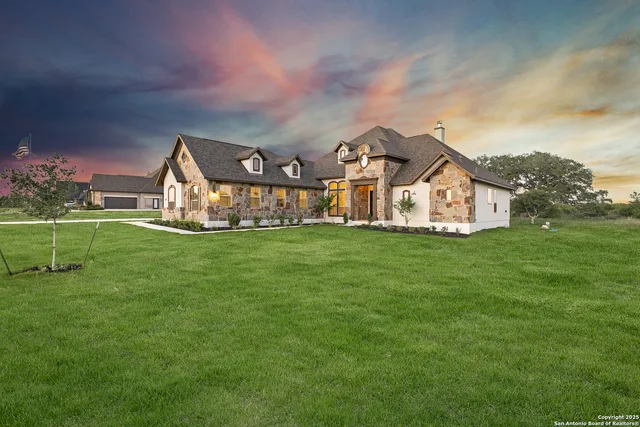 a view of a house with a big yard and large trees