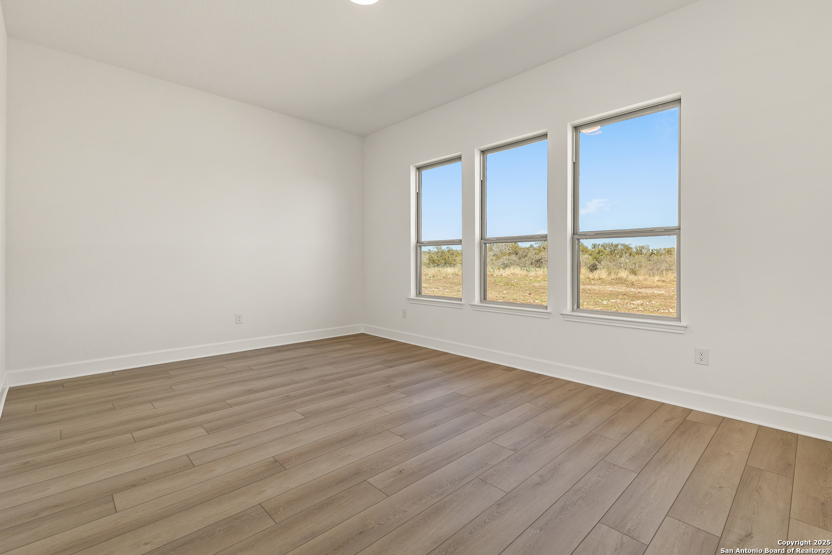 241 Stone Loop Castroville, TX 78009 - Photo 21 of 37 a view of an empty room with wooden floor and a window