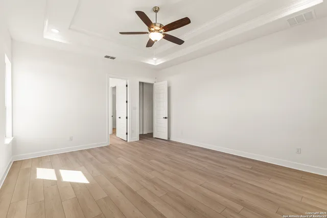an empty room with wooden floor and a ceiling fan