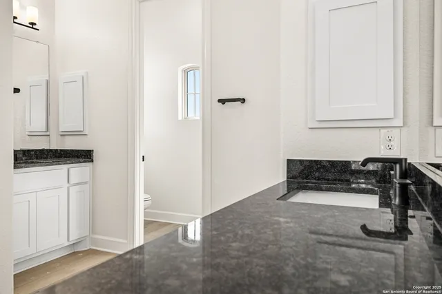 a kitchen with white cabinets and sink