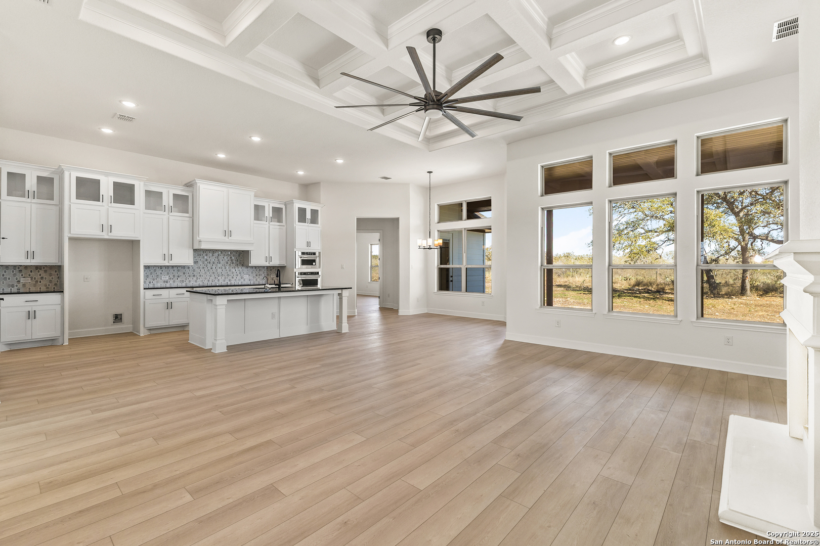 241 Stone Loop Castroville, TX 78009 - Photo 6 of 23 a view of an empty room with wooden floor and a kitchen