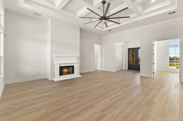 a view of an empty room with wooden floor and a fireplace