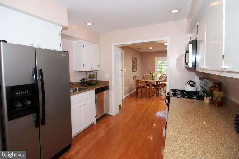 5631 Inverchapel Road Springfield, VA 22151 - Photo 11 of 30 a kitchen with stainless steel appliances a refrigerator a stove a sink a dining table and chairs with wooden floor