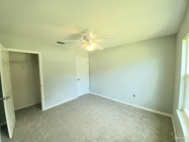 an empty room with a ceiling fan and a window