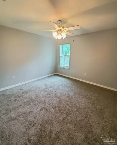 an empty room with windows and chandelier fan
