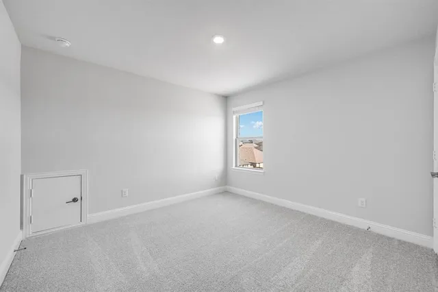 a view of an empty room with closet and a window