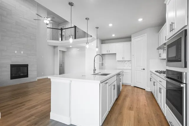 a kitchen with stainless steel appliances granite countertop a sink a stove and a wooden floors