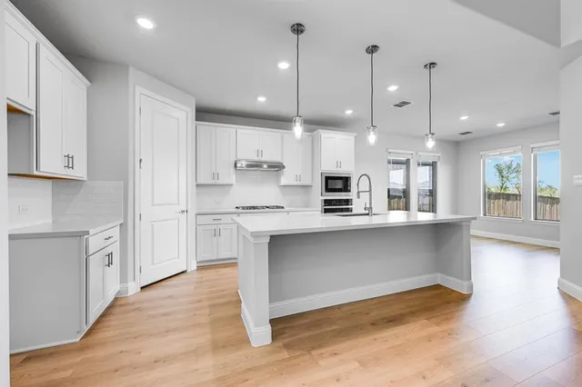 a large kitchen with granite countertop a large counter top a sink stainless steel appliances and cabinets