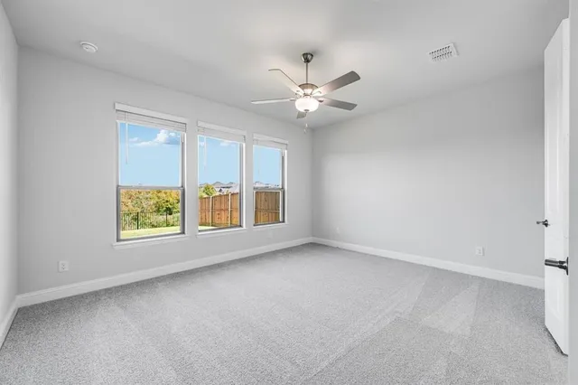 an empty room with windows and fan