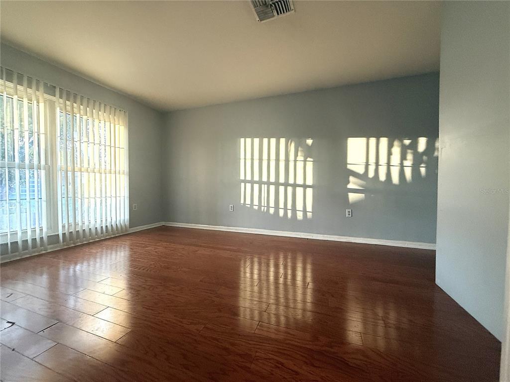 8840 Martinique Lane Port Richey, FL 34668 - Photo 12 of 31 an empty room with wooden floor and windows