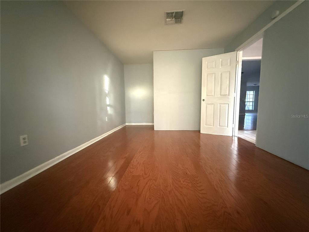 8840 Martinique Lane Port Richey, FL 34668 - Photo 13 of 31 an empty room with wooden floor and windows with curtains