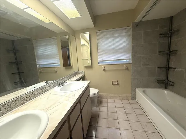 a bathroom with a granite countertop sink a mirror and a bathtub