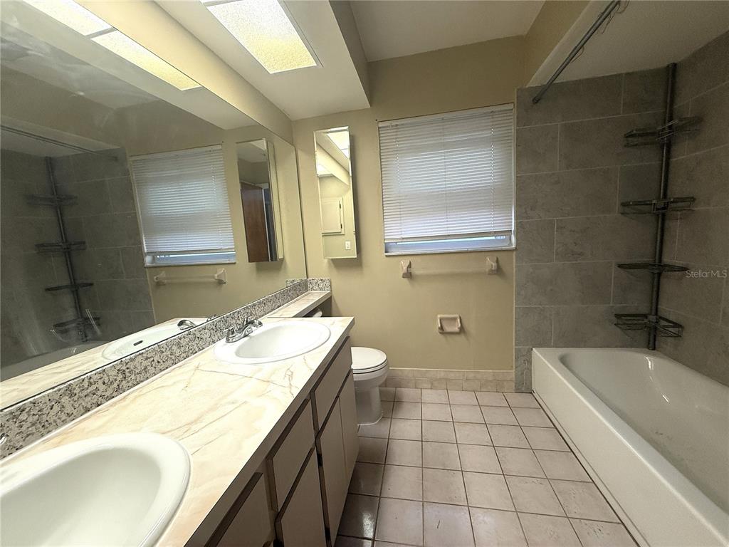 8840 Martinique Lane Port Richey, FL 34668 - Photo 15 of 31 a bathroom with a granite countertop sink a mirror and a bathtub