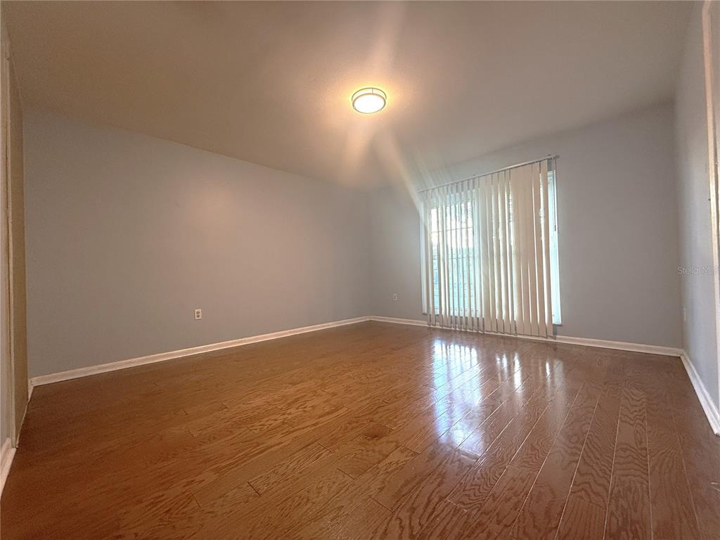 8840 Martinique Lane Port Richey, FL 34668 - Photo 16 of 31 a view of an empty room with wooden floor and a window