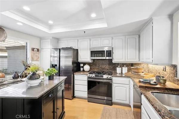 a kitchen with stainless steel appliances granite countertop a sink stove refrigerator and cabinets