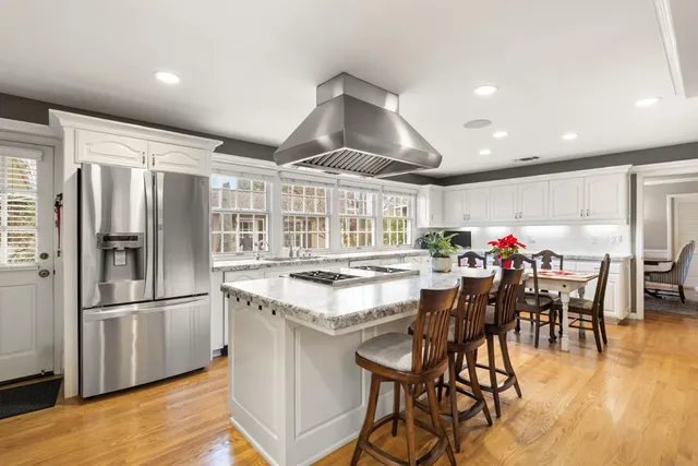 a kitchen with stainless steel appliances granite countertop a table chairs stove and refrigerator