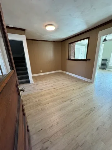 a view of an empty room with wooden floor and stairs