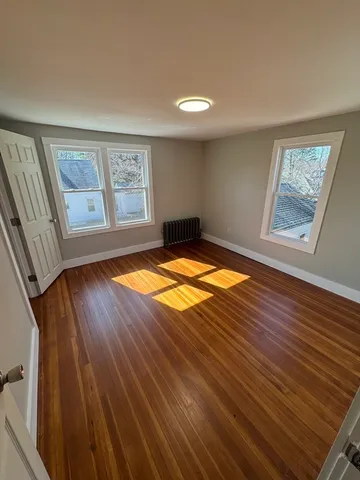 a view of an empty room with window and wooden floor