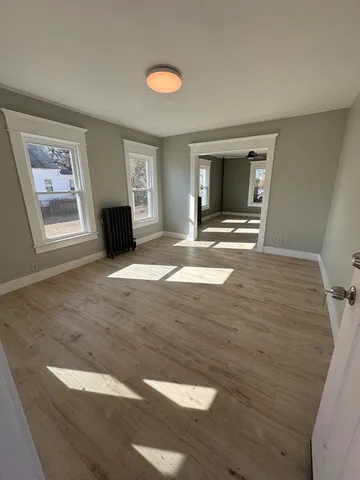 a view of empty room with wooden floor and fan