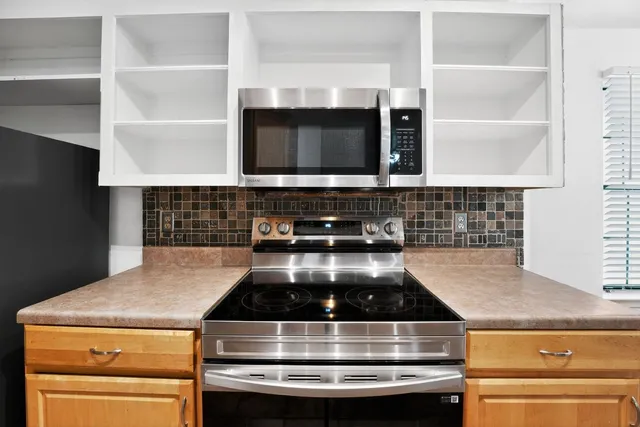 a kitchen view with granite countertop a refrigerator and a stove top oven