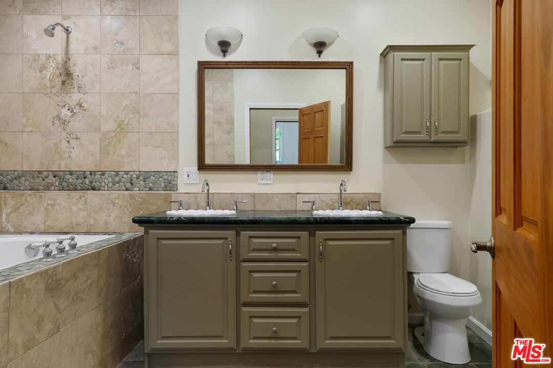 20912 Fontaine Road Topanga, CA 90290 - Photo 37 of 52 a bathroom with a granite countertop toilet sink and mirror