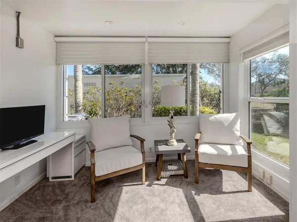 a living room with furniture a flat screen tv and a floor to ceiling window