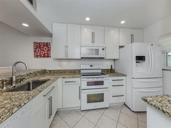 a kitchen with granite countertop white cabinets and white appliances
