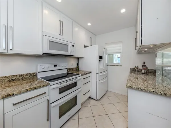 a kitchen with granite countertop a sink stove and cabinets