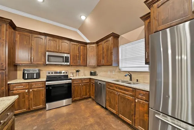 a kitchen with stainless steel appliances granite countertop white cabinets a sink dishwasher a stove and a refrigerator with wooden floor