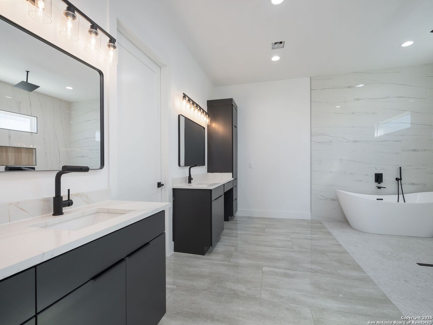 10907 Nina Ridge San Antonio, TX 78255 - Photo 22 of 54 a spacious bathroom with a double vanity sink a mirror and a bathtub