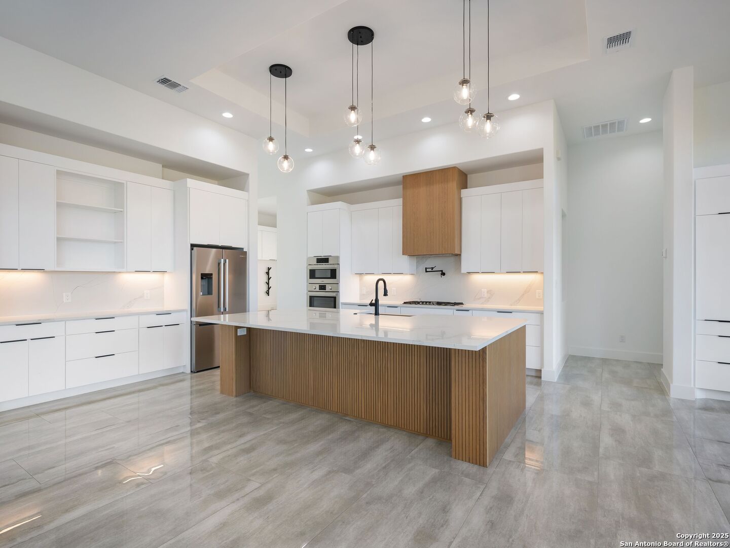 10907 Nina Ridge San Antonio, TX 78255 - Photo 7 of 54 a large white kitchen with kitchen island a sink dishwasher a stove and a refrigerator with wooden floor
