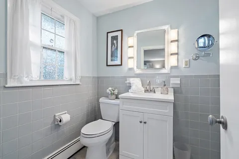 a bathroom with a granite countertop toilet a sink a mirror and a window