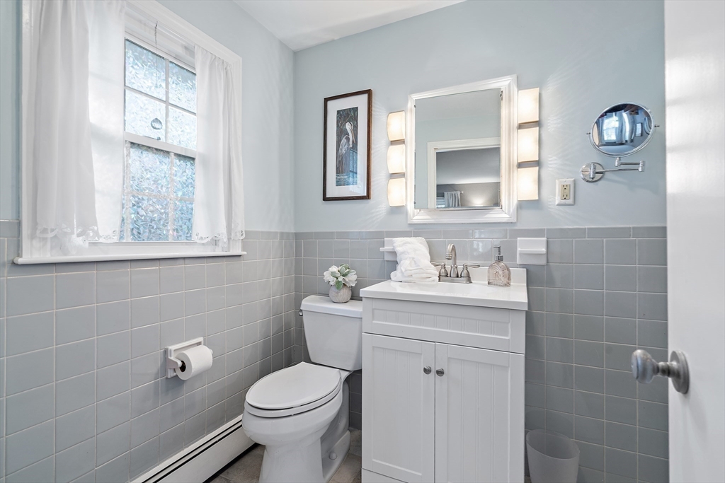 16 Beaudry Street Marlborough, MA 01752 - Photo 17 of 40 a bathroom with a granite countertop toilet a sink a mirror and a window