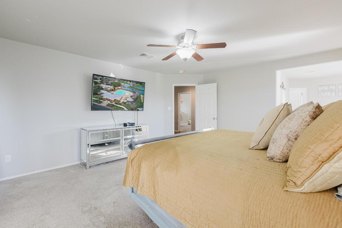 1420 Crested Butte Way Georgetown, TX 78626 - Photo 21 of 40 Primary Bedroom featuring light carpet, ensuite bath, and ceiling fan