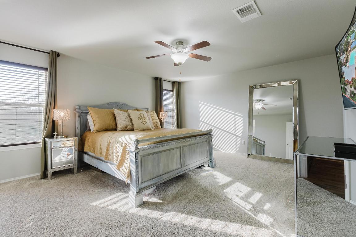1420 Crested Butte Way Georgetown, TX 78626 - Photo 22 of 40 Primary Bedroom featuring light carpet, ensuite bath, and ceiling fan