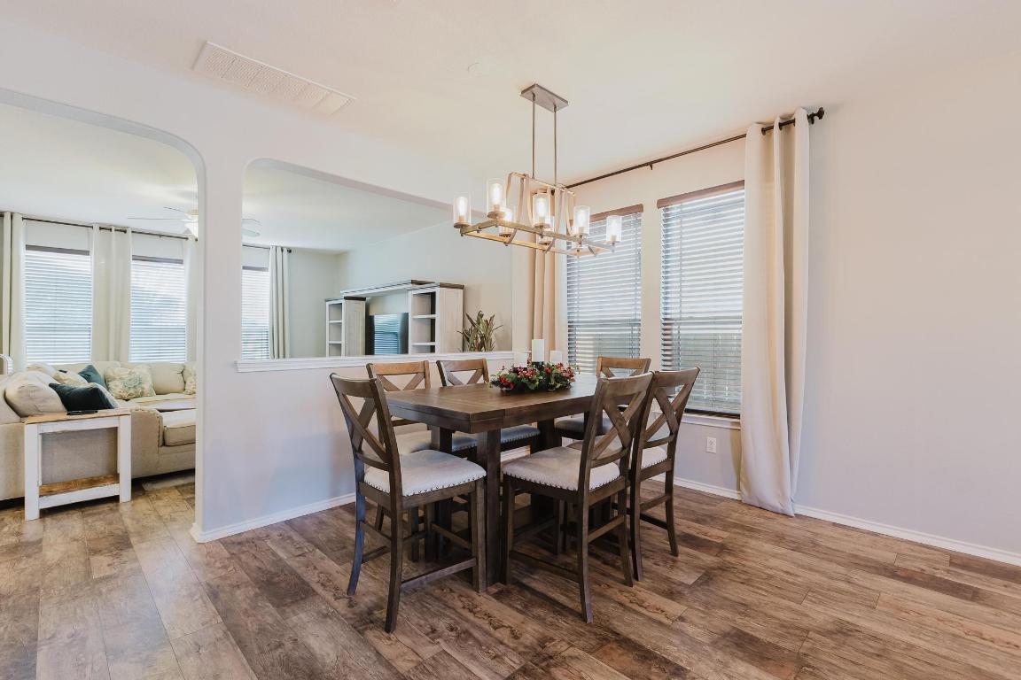 1420 Crested Butte Way Georgetown, TX 78626 - Photo 6 of 40 Dining space featuring wood-type flooring, ceiling fan, a chandelier, and healthy amount of natural light (chandelier will be switched prior to closing - photo in documents)