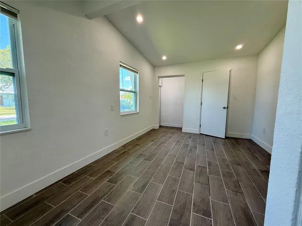 a view of an empty room with wooden floor and a window
