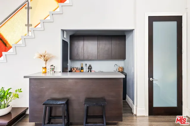a living room with stainless steel appliances kitchen island a table chairs in it and wooden floor