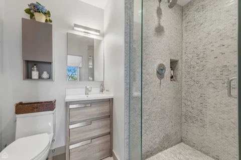 a bathroom with a granite countertop sink toilet a mirror and shower