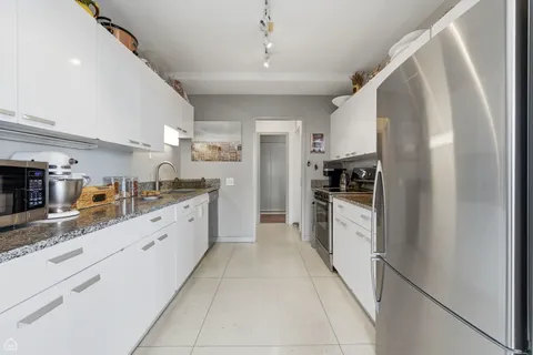 a large kitchen with granite countertop a large counter top space appliances and cabinets