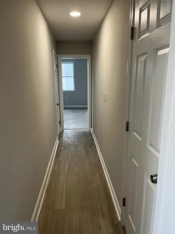 a view of a hallway with wooden floor and a bathroom