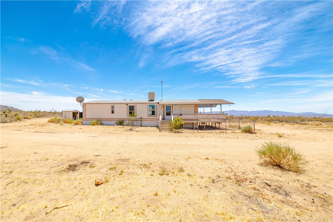 16435 South Wyatt Earp Road Yucca, AZ 86438 - Photo 53 of 57 Single-story residence featuring an elevated covered porch, light-colored siding, and a detached outbuilding