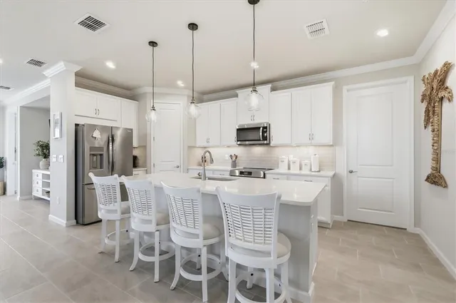 a kitchen with stainless steel appliances kitchen island granite countertop a table chairs sink and cabinets