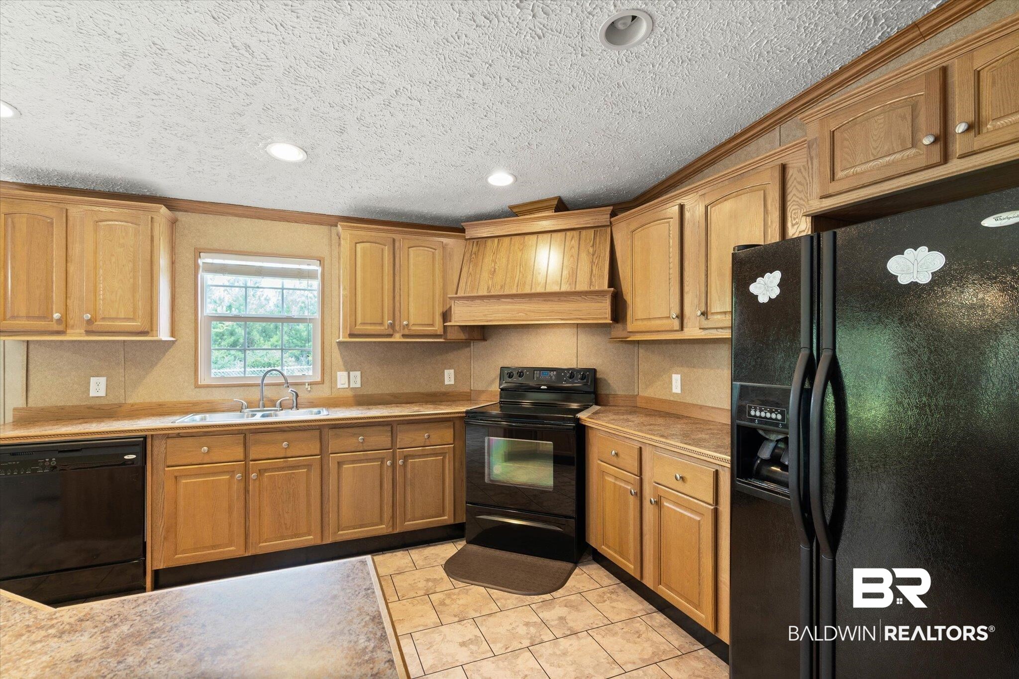 9335 Nathan Jordan Road Millry, AL 36558 - Photo 6 of 20 Kitchen featuring black appliances, premium range hood, light countertops, crown molding, and light tile patterned flooring