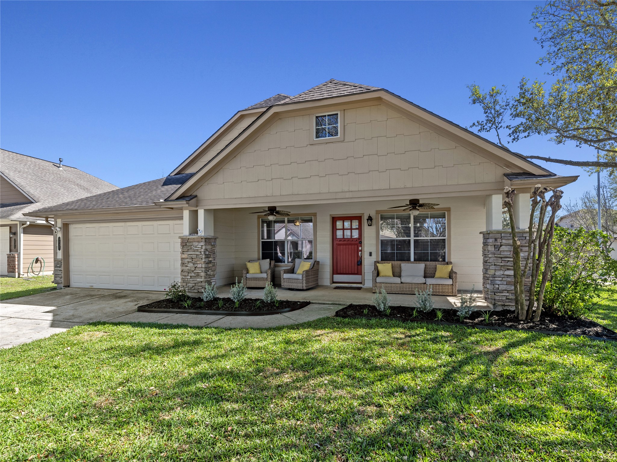 5727 Valley Scene Way Spring, TX 77379 - Photo 2 of 37 Cozy seating and ceiling fans on a oversized front porch. The exterior boasts a blend of stone and hardiplank siding, complemented by a red front door. A well-maintained lawn and attached two-car garage complete the curb appeal.