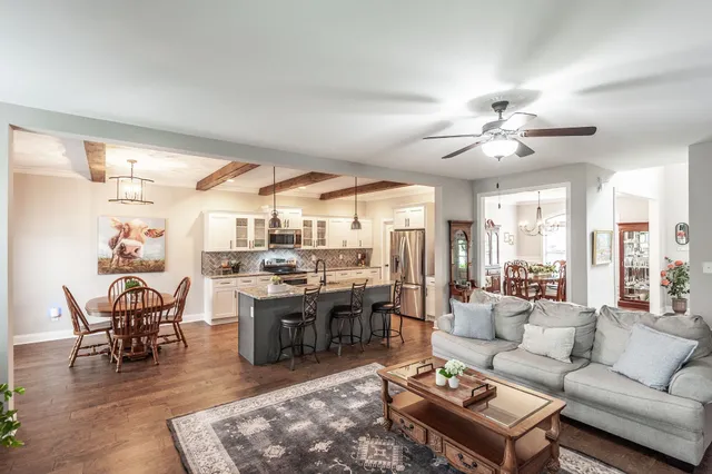 a living room with furniture kitchen view and a large window