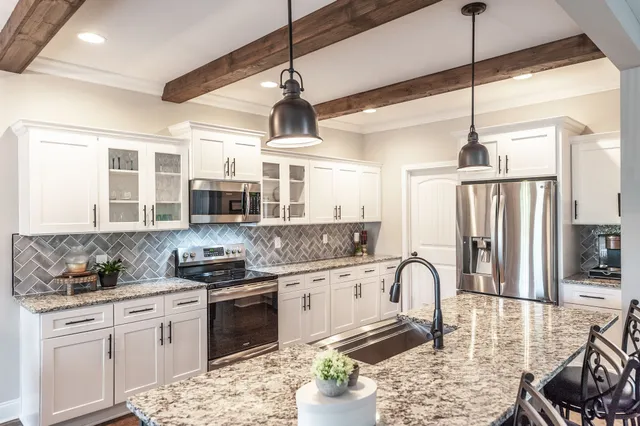 a kitchen with stainless steel appliances granite countertop a stove a sink dishwasher a refrigerator with white cabinets and wooden floor